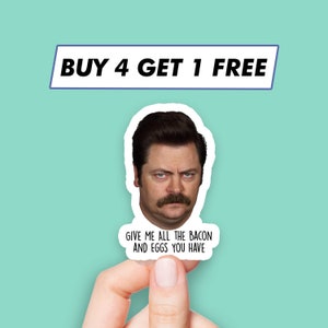 K&ouml;nnte beinhalten: Ein wei&szlig;er Aufkleber mit einem Bild von Ron Swanson aus der Serie Parks and Recreation. Der Aufkleber lautet "Gib mir all den Speck und die Eier, die du hast".