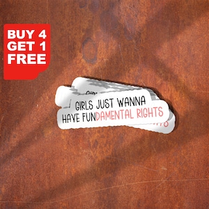 Op de afbeelding: Witte stickers met de tekst "GIRLS JUST WANNA HAVE FUNDAMENTAL RIGHTS" in zwarte en roze letters. Een rode hoek met de tekst "BUY 4 GET 1 FREE" staat in de linkerbovenhoek. De achtergrond is roestbruin.