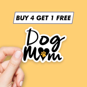 May include: Black and white sticker with the text "Dog Mom" and a black heart with a gold paw print inside. The sticker is on a yellow background with the text "BUY 4 GET 1 FREE" above it.