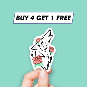 Puede incluir: Un lobo blanco aullando con rosas rosas y hojas verdes alrededor de su cabeza. La pegatina dice "COMPRA 4, LLEVA 1 GRATIS".