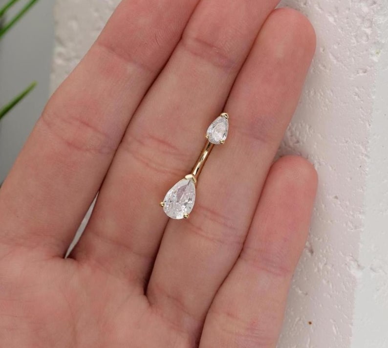 Puede incluir: Joyer&iacute;a corporal de oro con dos piedras transparentes en forma de l&aacute;grima.