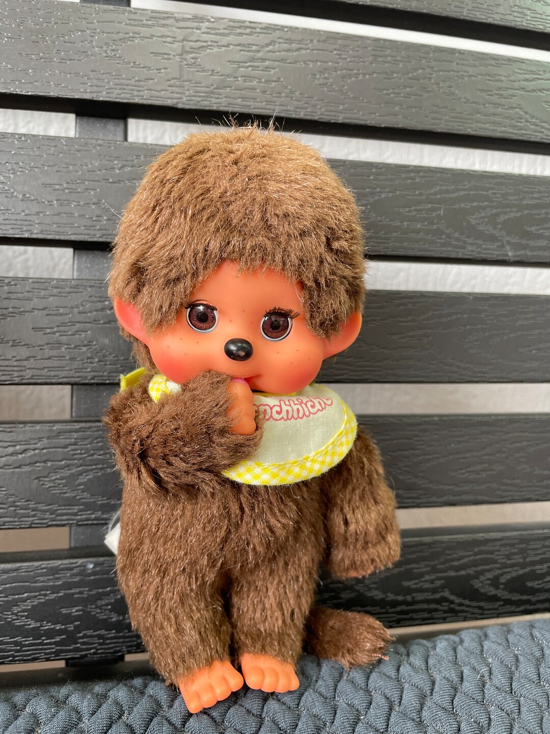 茶色のかわいいモンチッチのまばたき目が親指を吸っている