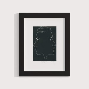 May include: Black and white line art print of two faces looking in opposite directions. The print is framed in a black frame and has the text "Mark 1943" and "A. Kollmar" at the bottom.