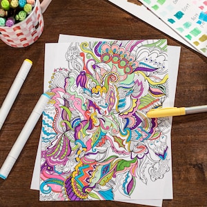 Puede incluir: Una página para colorear en blanco y negro con un diseño detallado e intrincado de remolinos, líneas y formas en una variedad de colores. La página está sobre una mesa de madera con dos marcadores blancos y un marcador amarillo.