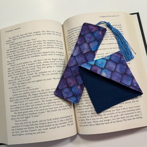 May include: Two purple and blue patterned fabric bookmarks with a blue tassel. One bookmark is a long rectangle and the other is a triangle.