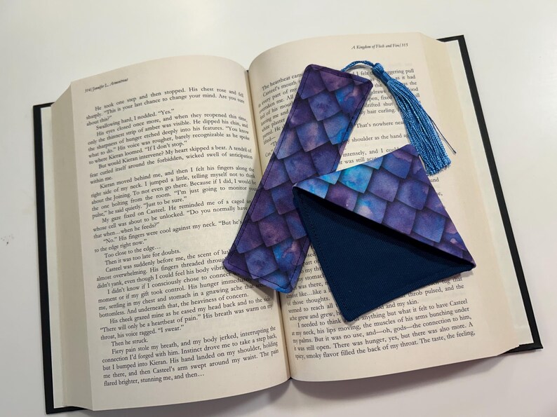 May include: Two purple and blue patterned fabric bookmarks with a blue tassel. One bookmark is a long rectangle and the other is a triangle.
