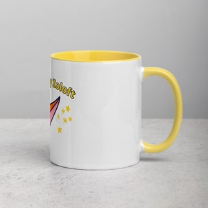 Puede incluir: Taza de cer&aacute;mica blanca con borde y asa amarillos. La taza tiene un cohete de dibujos animados rosa y naranja con el texto "Happy Zoloft" en amarillo.