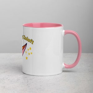 Puede incluir: Taza de cer&aacute;mica blanca con borde y asa de color rosa. La taza tiene una ilustraci&oacute;n rosa y amarilla de un cohete con estrellas y el texto "Happy Zoloft".