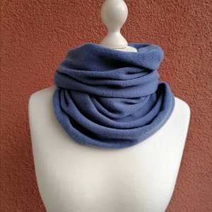 Peut inclure: Un tour de cou ou cache-cou en tricot bleu, plié et présenté sur un mannequin blanc. Le tour de cou est fait d'un tissu doux et extensible.