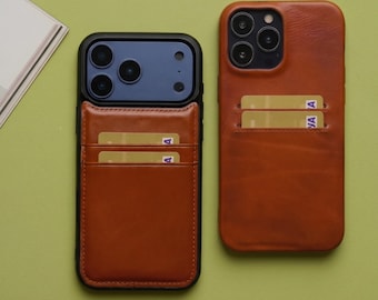 Puede incluir: Dos fundas para smartphone hechas de cuero marrón liso, cada una con ranuras para tarjetas integradas en la parte posterior. Una funda está colocada en un smartphone con un módulo de cámara azul oscuro, mientras la otra se muestra sola.