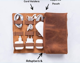 Puede incluir: Un organizador de viaje de cuero marrón con una bolsa con cremallera, portacables y compartimentos para adaptadores y accesorios.