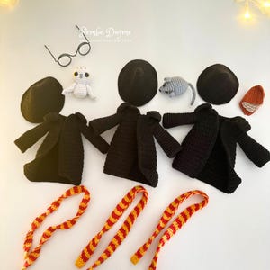 May include: Crocheted amigurumi toys and accessories, including black coats, hats, and scarves with red and yellow stripes. Also included are a white owl, a gray mouse, and round glasses.