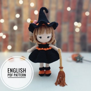 May include: Crochet pattern for a witch doll with a black dress, orange and black shoes, a black witch hat with a pink flower, and a brown broom.