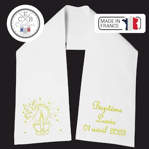Peut inclure: Sash en tissu blanc avec broderie dorée d'une colombe, d'une bougie et d'un soleil éclatant. Le texte "Bapteme Louis 01 avril 2023" est également brodé en or.