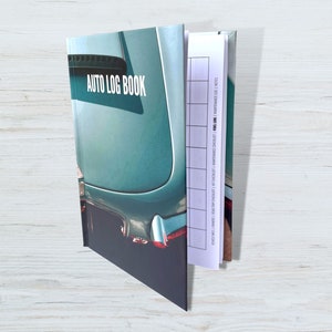 May include: A blue and white auto log book with a vintage car on the cover. The book has a gridded section for recording information about car maintenance.