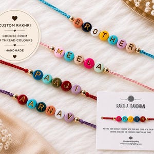 May include: Four custom Rakhi bracelets featuring colourful round beads with gold letters spelling BROTHER, MEELA, PAAJI, and AARNAV, strung on vibrant threads. A white display card shows a red bracelet with the name ARJUN and text.