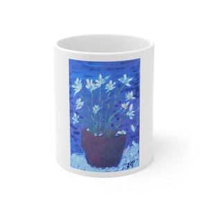 May include: A white ceramic mug with a black handle and the text "But First, Coffee" in a black, bold font. The mug is on a white surface.