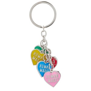 May include: A silver key chain with a silver ring and five heart-shaped charms. The charms are colored green, yellow, blue, red, and pink. Each charm has the words "HUMAN MADE" printed on it in white.