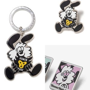 Könnte beinhalten: Eine Sammlung von Human Made-Accessoires mit einem Cartoon-Hasen-Design. Enthält einen Schlüsselanhänger, eine Anstecknadel und eine rechteckige Anstecknadel mit dem Text "Human Made Seoul". Der Hase hat schwarze Ohren und Füße, ein weißes Gesicht und eine gelbe herzförmige Brust.
