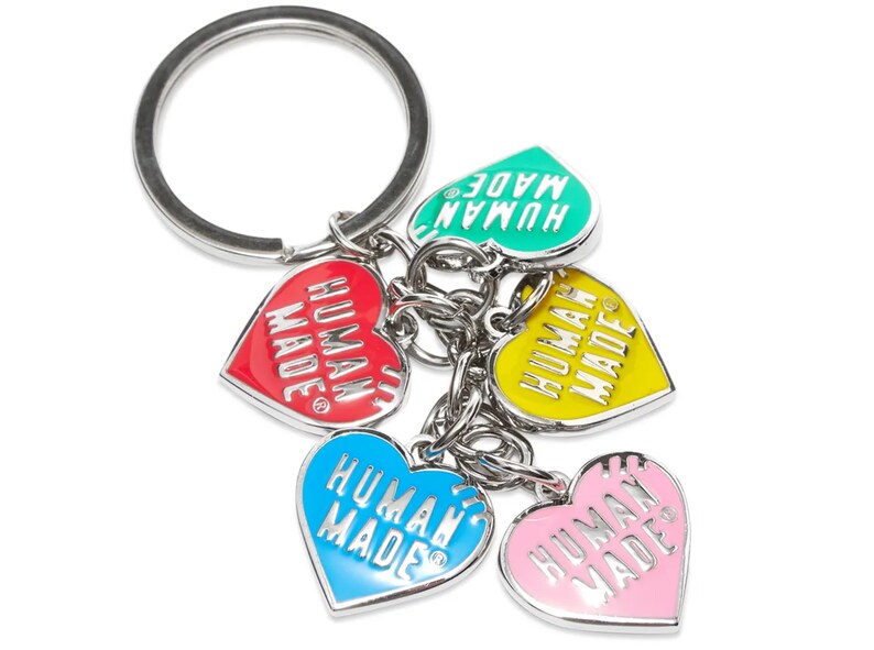 May include: A silver key chain with five heart-shaped charms. Each charm is a different color: green, red, yellow, blue, and pink. Each charm has the text "HUMAN MADE" printed on it.