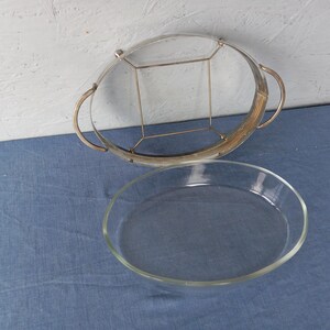 May include: A silver serving tray with a glass insert. The tray has a decorative wire design and two handles. The glass insert is clear and oval shaped.