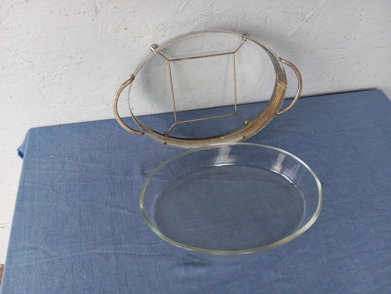 May include: A silver serving tray with a glass insert. The tray has a decorative wire design and two handles. The glass insert is clear and oval shaped.