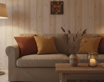Könnte beinhalten: Ein beiges Sofa mit zwei rostfarbenen und zwei senfgelben Zierkissen. Vor dem Sofa steht ein hölzerner Couchtisch mit einer Keramikvase, die getrocknete Gräser enthält, sowie einem Glaswindlicht mit einer weißen Stumpenkerze.