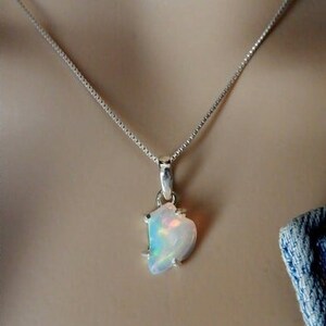 May include: A silver chain necklace with a pendant featuring a white opal gemstone with iridescent rainbow colors.