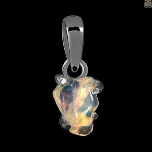 May include: A silver pendant featuring a raw, iridescent opal gemstone. The opal is set in a silver bezel and has a rough, natural shape.