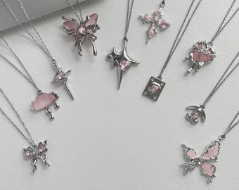 May include: Nine silver necklaces with pink crystal pendants. The pendants include a butterfly, a cross, a star, a heart, a cloud, and a dripping heart.
