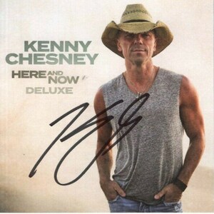 Puede incluir: La portada del álbum de Kenny Chesney "Here and Now" Deluxe Edition. La portada presenta una foto de Kenny Chesney con un sombrero de paja y una camiseta sin mangas gris. Su firma está en tinta negra en la esquina inferior izquierda de la imagen.