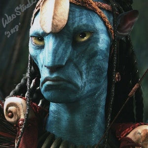 May include: A blue-skinned alien with a serious expression, wearing a brown leather headband and a bone necklace. The alien has long black braids and large, yellow eyes. The image is signed "Wes Studi 2009".