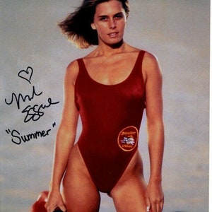 May include: A woman in a red swimsuit with a "Baywatch Lifeguard" patch, holding a red rescue can. The image includes the handwritten text "Summer" and a signature.