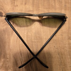 May include: Black and white striped sunglasses with black frames. The sunglasses are folded in half and the frames are crossed.