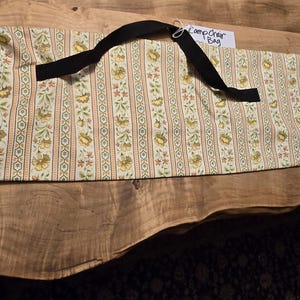 May include: A white and yellow striped fabric camp chair bag with a black strap and the text "Camp Chair Bag" on a tag.