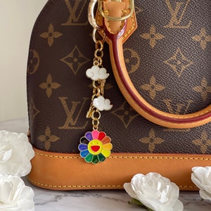 Dije para bolso o cartera con diseño de girasol sonriente y nubes o margaritas de arcoíris.