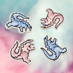 Op de afbeelding: Vier geborduurde strijkpatches met cartoon-dinosaurussen in roze en blauw. De dinosaurussen staan in verschillende poses, waaronder staand, lopend en brulend.