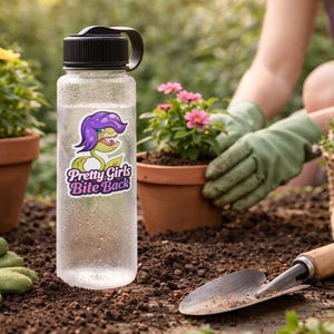 May include: A clear water bottle with a black lid and a sticker that reads "Pretty Girls Bite Back" featuring a cartoon Venus flytrap with purple hair. The bottle is surrounded by gardening tools and plants in terracotta pots.