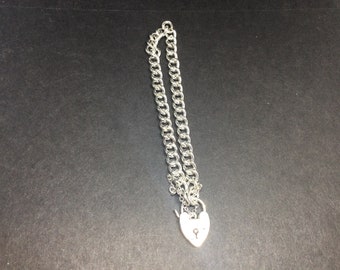 May include: A silver chain necklace with a heart-shaped padlock clasp.
