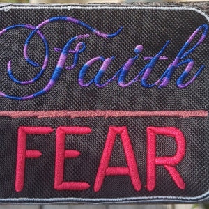 May include: Embroidered patch with the words "Faith" in blue and purple script above a red line and the word "FEAR" in red block letters. The patch has a black background and a white border.