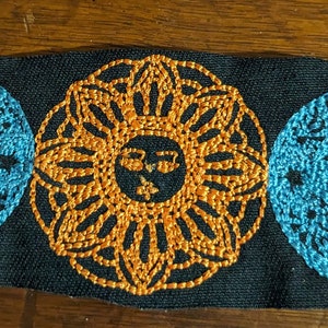 May include: Embroidered patch with a triple moon design. The moon is blue and the sun is orange. The sun is in the center and the moons are on either side.