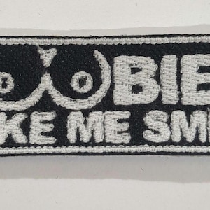 May include: A black embroidered patch with white stitching that reads "Boobies Make Me Smile".