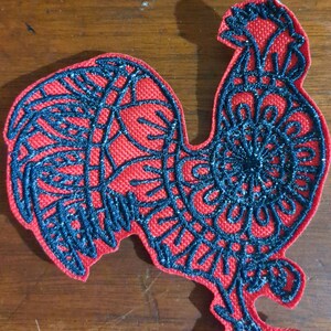 May include: A red embroidered patch of a rooster with black detailed lines. The rooster is facing right and has a large comb and wattle.
