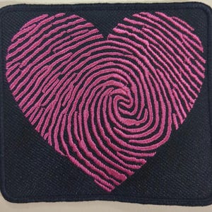 Può includere: Toppa ricamata con un cuore a impronta digitale rosa su sfondo quadrato nero. Il cuore, con il suo motivo dettagliato, è centrato e incorniciato da un bordo scuro. Adatta per personalizzare abbigliamento e accessori.