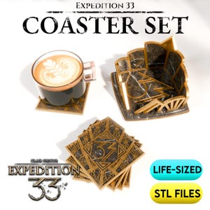 以下が含まれることがあります： 「EXPEDITION 33」と「COASTER SET」の文字が入ったコースターセット。幾何学模様の正方形コースター、ホルダー、コーヒーカップが含まれています。コースターは金と黒で、中央に数字の「33」が入っています。