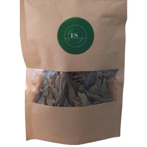 May include: A brown paper bag with a green circle sticker that says "ES Beauty & Wellness". The bag contains dried green leaves.