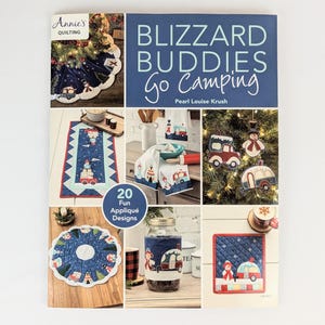 May include: A book cover for a quilting pattern book titled "Blizzard Buddies Go Camping" by Pearl Louise Krush. The cover features a collage of images of appliqued winter-themed designs, including a snowman, a camper, and a car. The book includes 20 fun applique designs.