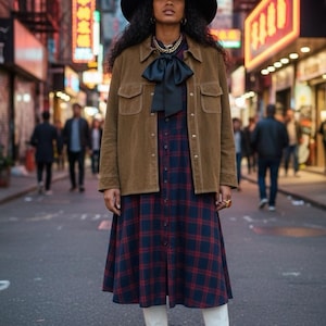 May include: A woman in a city street wearing a black hat, brown jacket, and a plaid dress. She is also wearing a black bow tie, gold jewelry, and white boots. The background features neon signs and blurred figures.