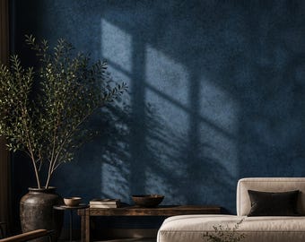 Könnte beinhalten: Ein Wohnzimmer mit einem beigen Ecksofa mit dunkelbraunen und beigen Kissen, einem braunen Ledersessel, einem dunklen Couchtisch aus Holz, einer großen dunklen Keramikvase mit einer grünen Pflanze und einer strukturierten dunkelblauen Wand.