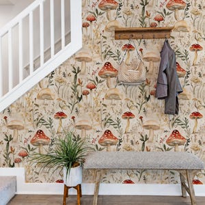 Puede incluir: Papel pintado con un patr&oacute;n bot&aacute;nico repetitivo de varios hongos, flores silvestres y follaje en tonos rojos, marrones y verdes sobre un fondo beige claro, aplicado en una pared junto a una escalera con un perchero y un banco.